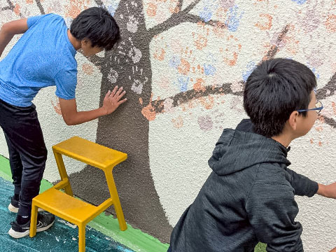 児童皆で手形を押していきます（2025年10月21日高槻市立安岡寺小学校50周年記念手形アート塗装）