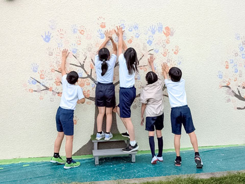 どんどん手形をつけていきます（2025年10月21日高槻市立安岡寺小学校50周年記念手形アート塗装）