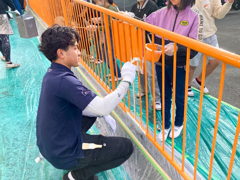 職人の刷毛捌きを見せる営業部本田（2025年10月31日高槻市立阿武野小学校ボランティア塗装）