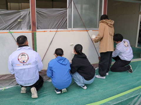 下足室外の壁を塗っています。左端は職人深水（2025年1月27日高槻市立安岡寺小学校 卒業生ボランティア塗装）