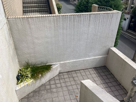 紫外線や雨水などにより擁壁の表面塗膜が劣化し、撥水機能が低下したために雨染みや黒ずみなどの汚れが付着しています。